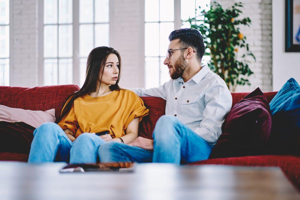 A man and woman sitting on a couch in a living room.